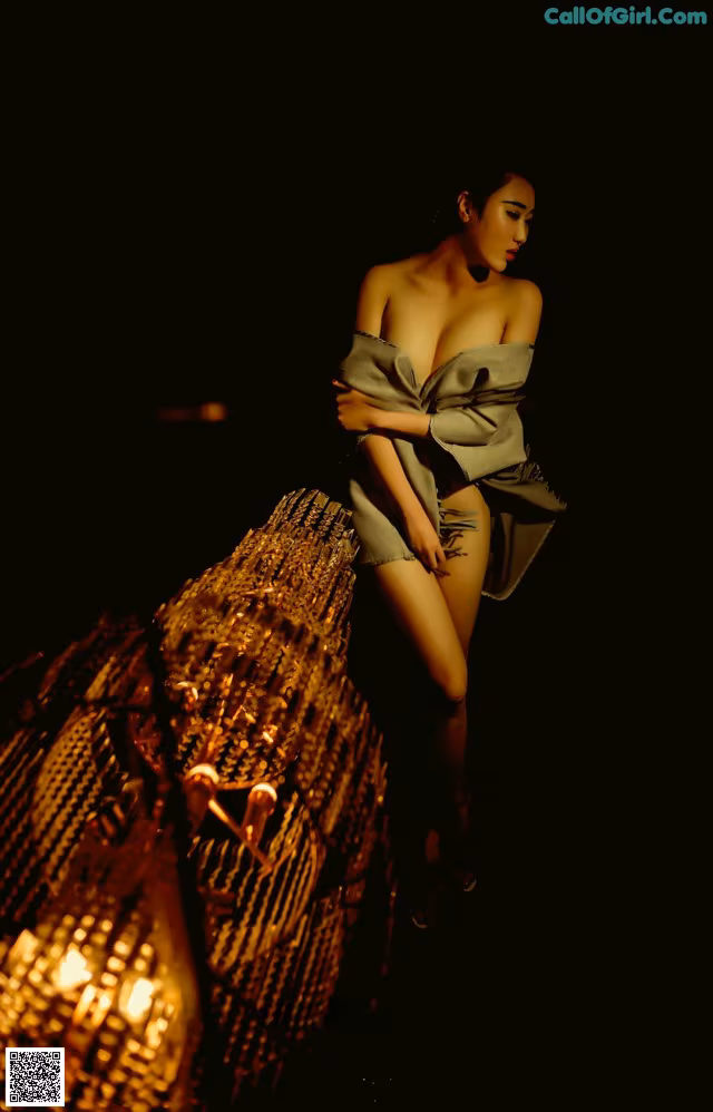 A woman in a gray dress standing next to a lamp.