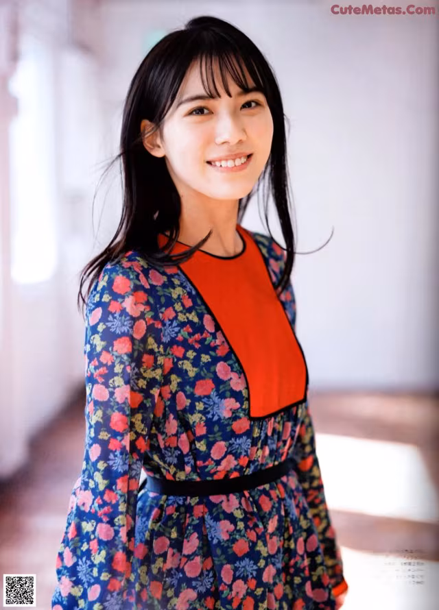 A woman in a blue and red dress posing for a picture.