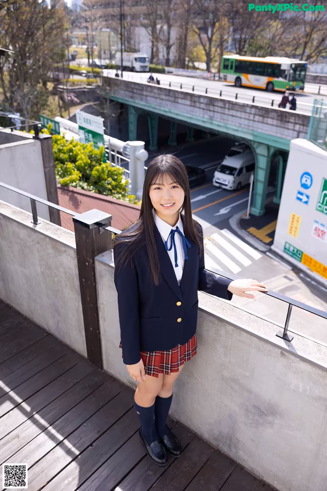 A woman in a school uniform standing on a bridge.