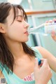 A woman drinking water from a bottle while holding a pill.