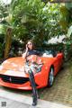 A woman sitting on top of a red sports car.