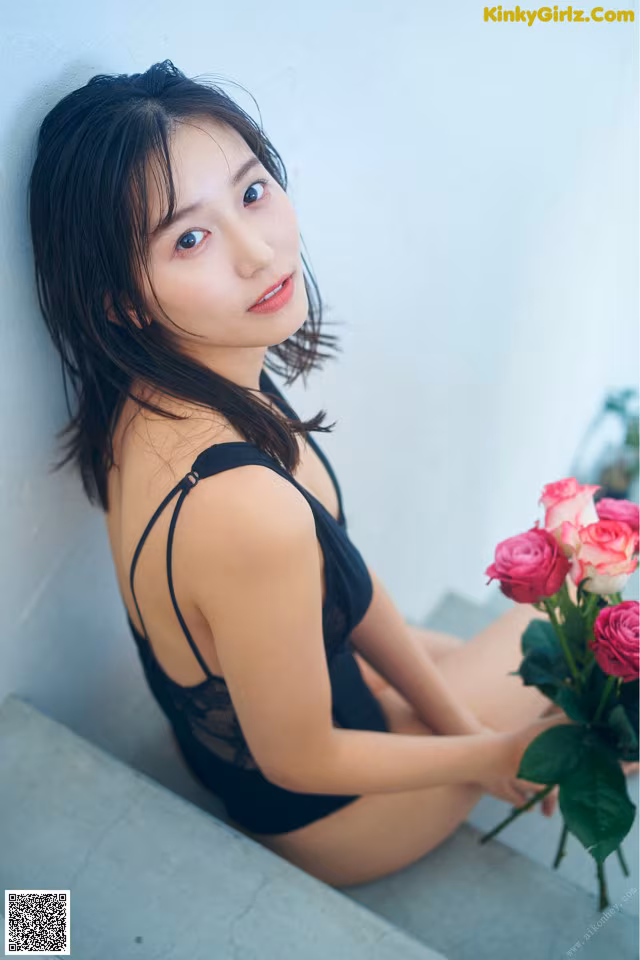 A woman in a black bathing suit holding a bunch of roses.