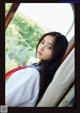 A woman in a school uniform looking out a window.