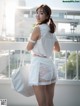 A woman in a white dress holding a white bag.