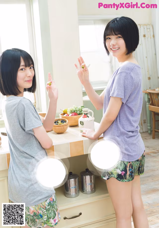 A couple of women standing next to each other in a kitchen.