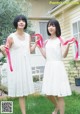 A couple of women standing next to each other in front of a house.