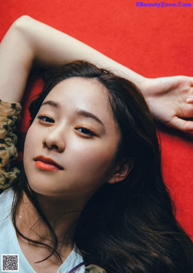 A woman laying on a red carpet with her hands behind her head.