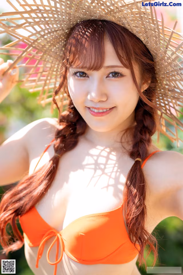 A woman in an orange bikini and a straw hat.