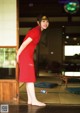 A woman in a red dress standing in front of a door.