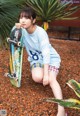 A young girl sitting on the ground holding a skateboard.