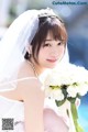 A woman in a wedding dress holding a bouquet of flowers.