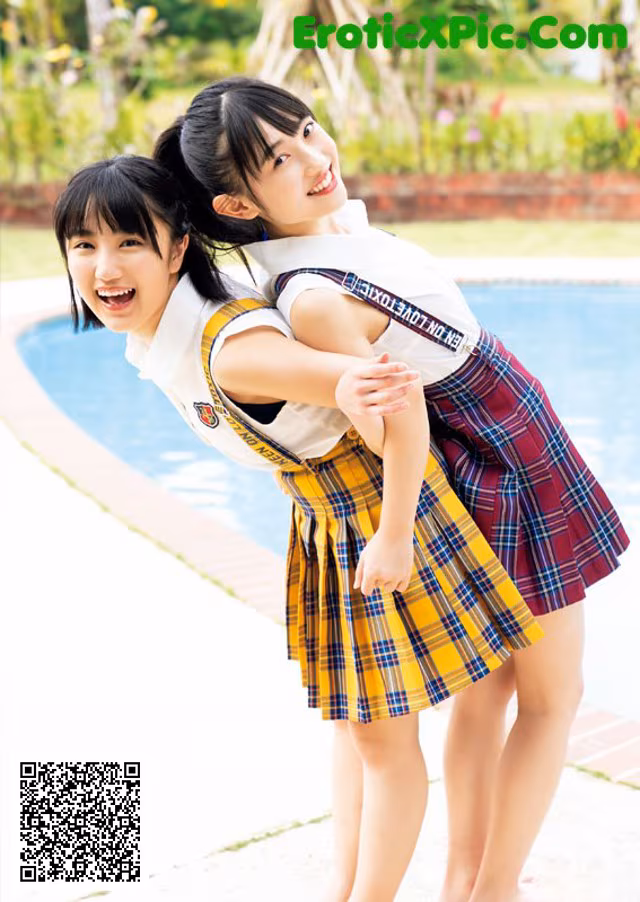 A couple of young women standing next to a swimming pool.