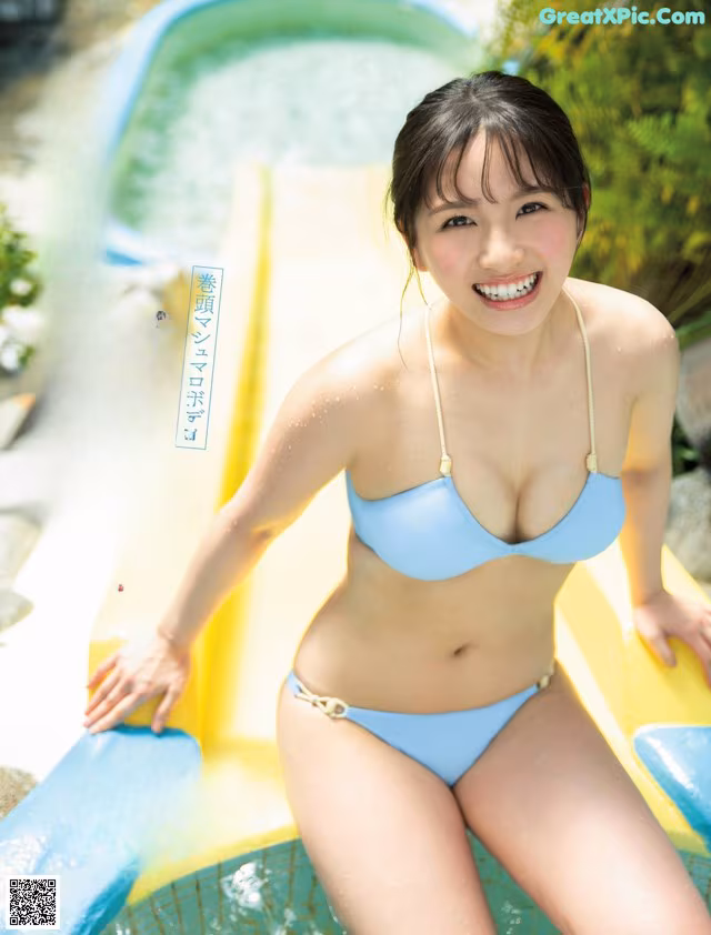 A woman in a blue bikini sitting on a yellow slide.