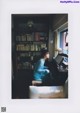 A woman sitting at a piano in front of a book shelf.