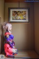 A woman in a pink and blue outfit sitting on a shelf.