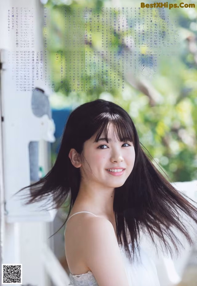 A woman with long black hair standing in front of a window.