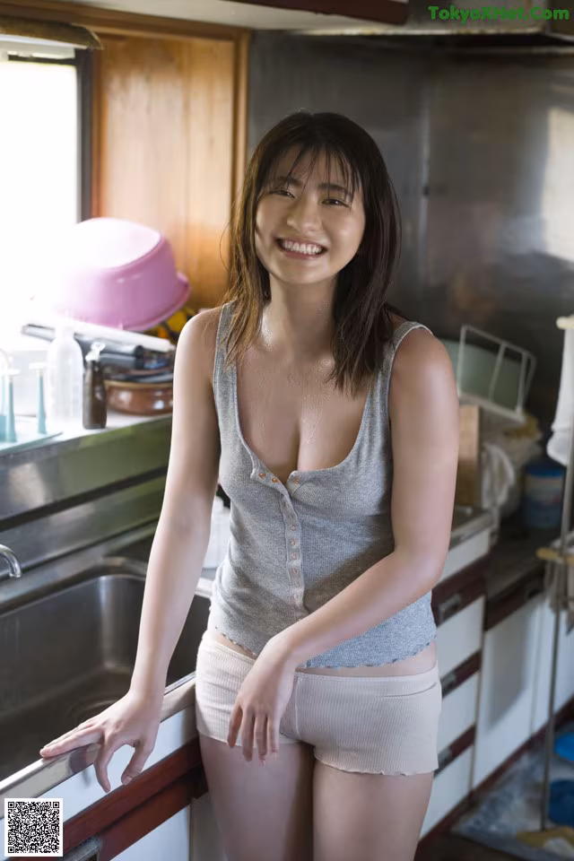 A woman standing in a kitchen next to a sink.