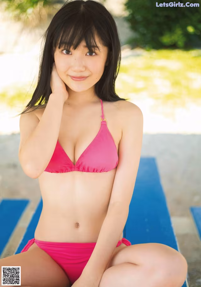 A woman in a pink bikini sitting on a blue bench.