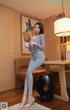 A woman sitting on a stool holding a cup of coffee.