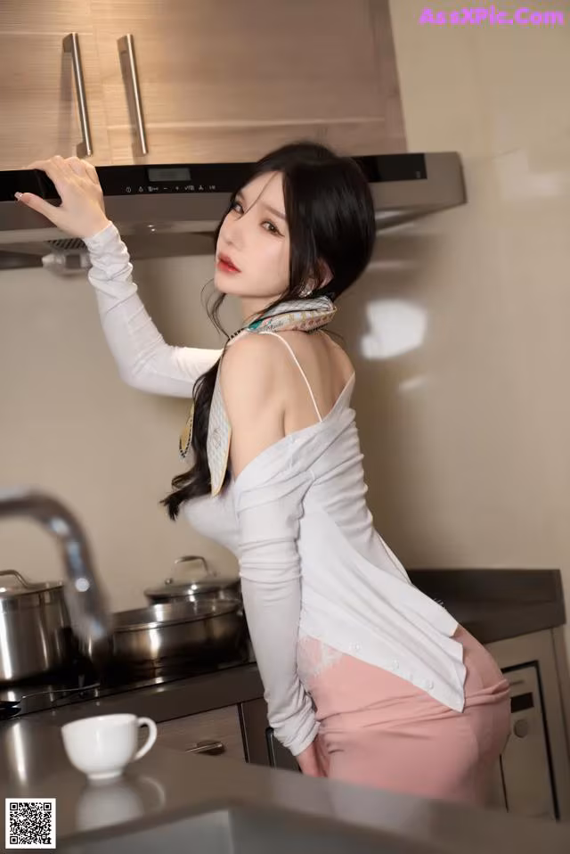 A woman standing in a kitchen next to a stove.